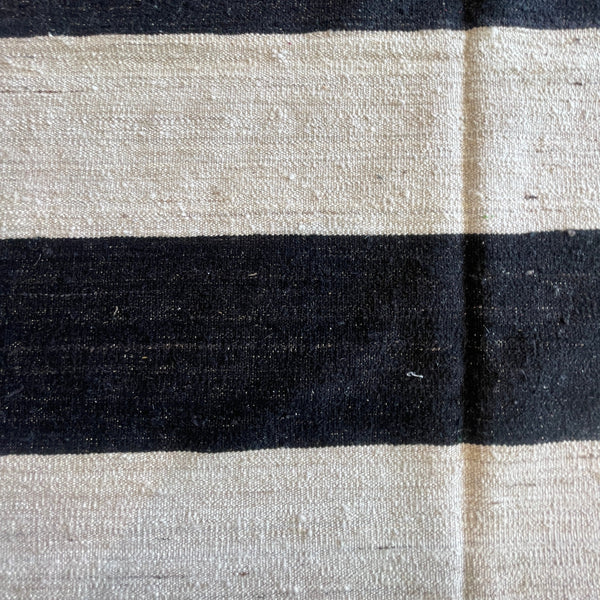 Closeup of white and black striped kilim rug