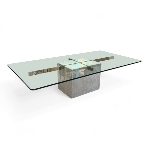 A coffee table with a travertine cube base, brass cross design, topped with a rectangular glass surface. 