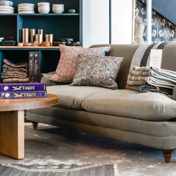 Custom velour sofa made in los angeles styled with vintage pillows in a furniture showroom