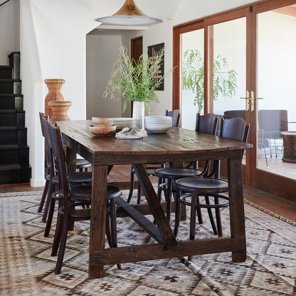 Rustic dining table in dark reclaimed wood with moroccan rug, vintage dekor and french bentwood chairs