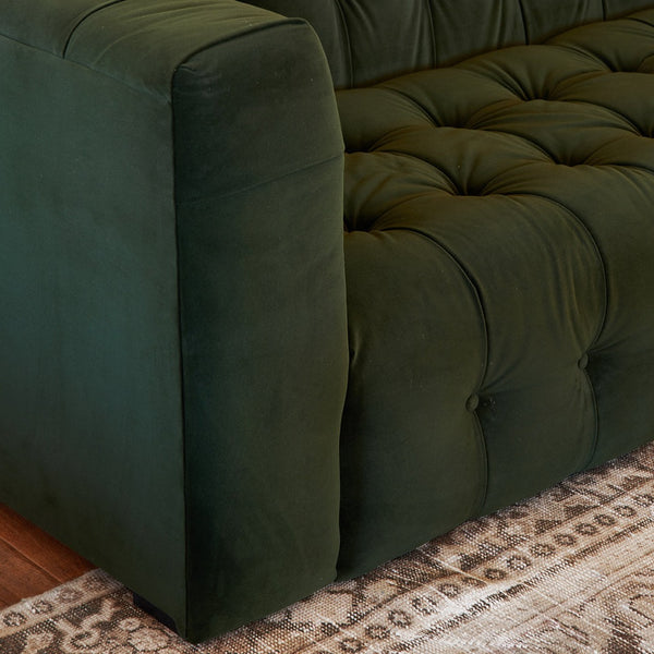 Close up of green velvet tufted sofa bench and block arm