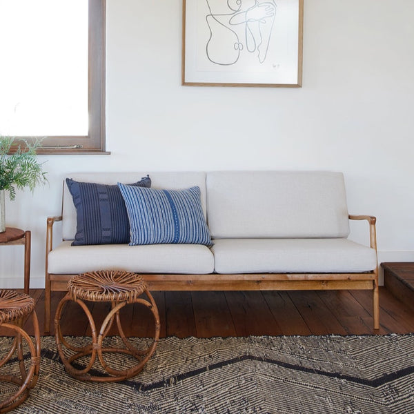 Natural finished MCM sofa with vintage home decor and moroccan beni rug and wicker stools