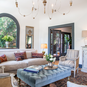 blue velvet upholstered ottoman under antique chandelier in hollywood hills home designed by celebrity interior designer isabelle dahlin