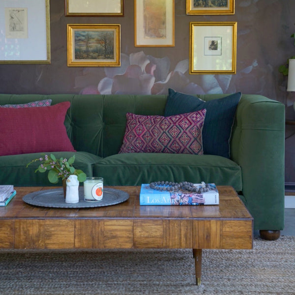 Green tufted sofa with custom plush cushions and mid century modern wood coffee table.