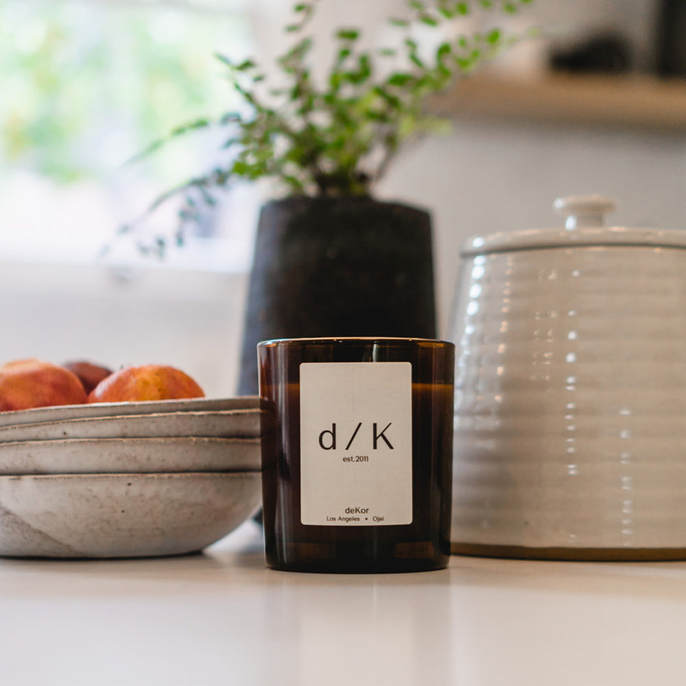 deKor d/K Organic Candle in an amber color glass jar with a wooden lid