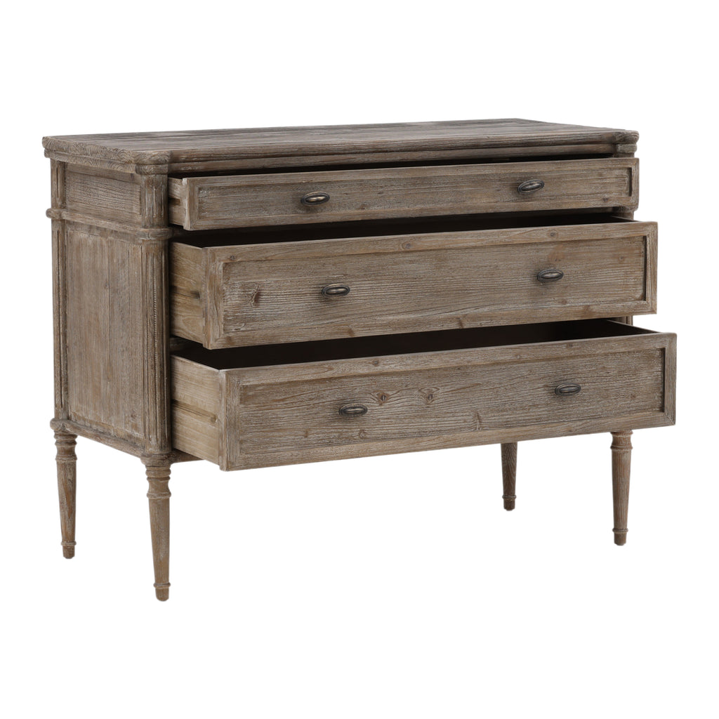 This dresser has a rectangular shape with three wide drawers and a weathered, rustic wood texture. The edges are softly rounded, and the small oval knobs have a smooth finish. Its slim, tapered legs feature subtle carved detailing, adding a refined touch. The overall look is simple yet elegant, with a pale, vintage-style finish.