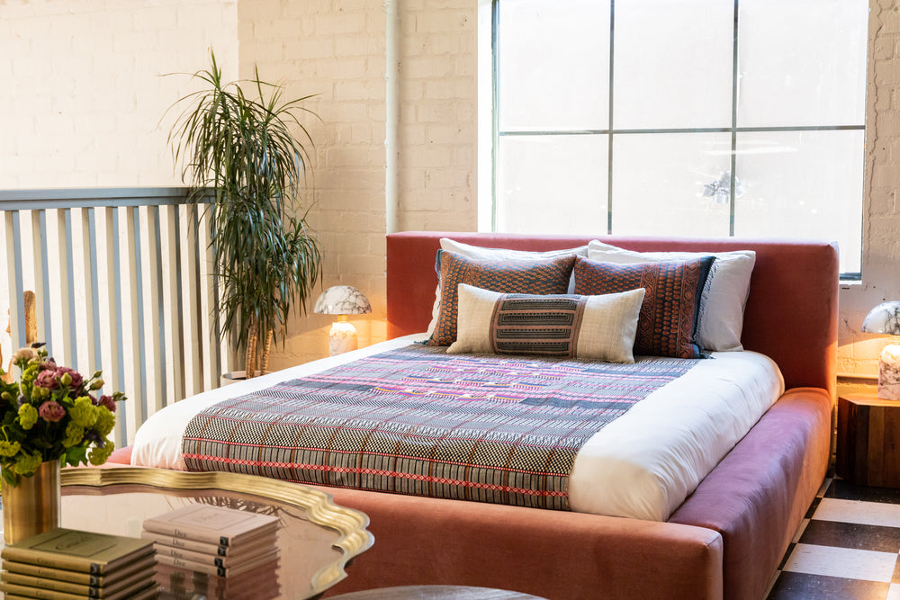 Custom velour upholstered queen bed with vintage pillows and modern silhouette 