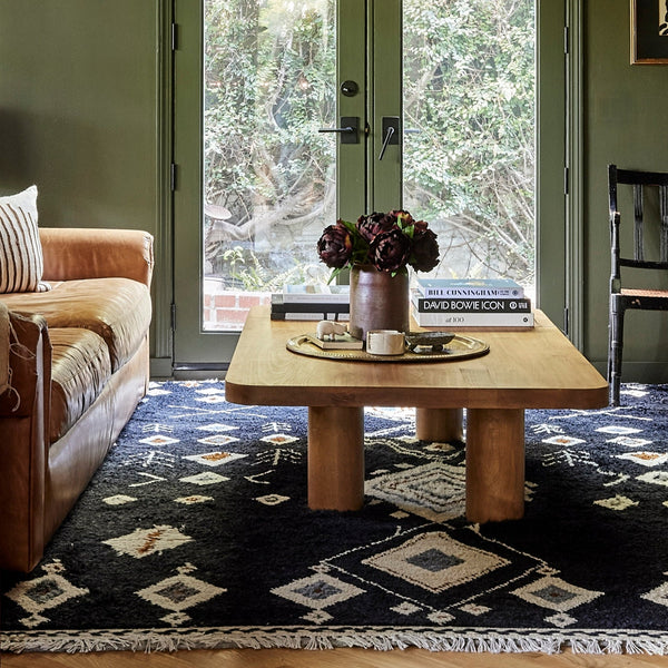 Modern coffee table in chestnut wood stain styled in a living room with green walls, leather sofe and vintage home decor 