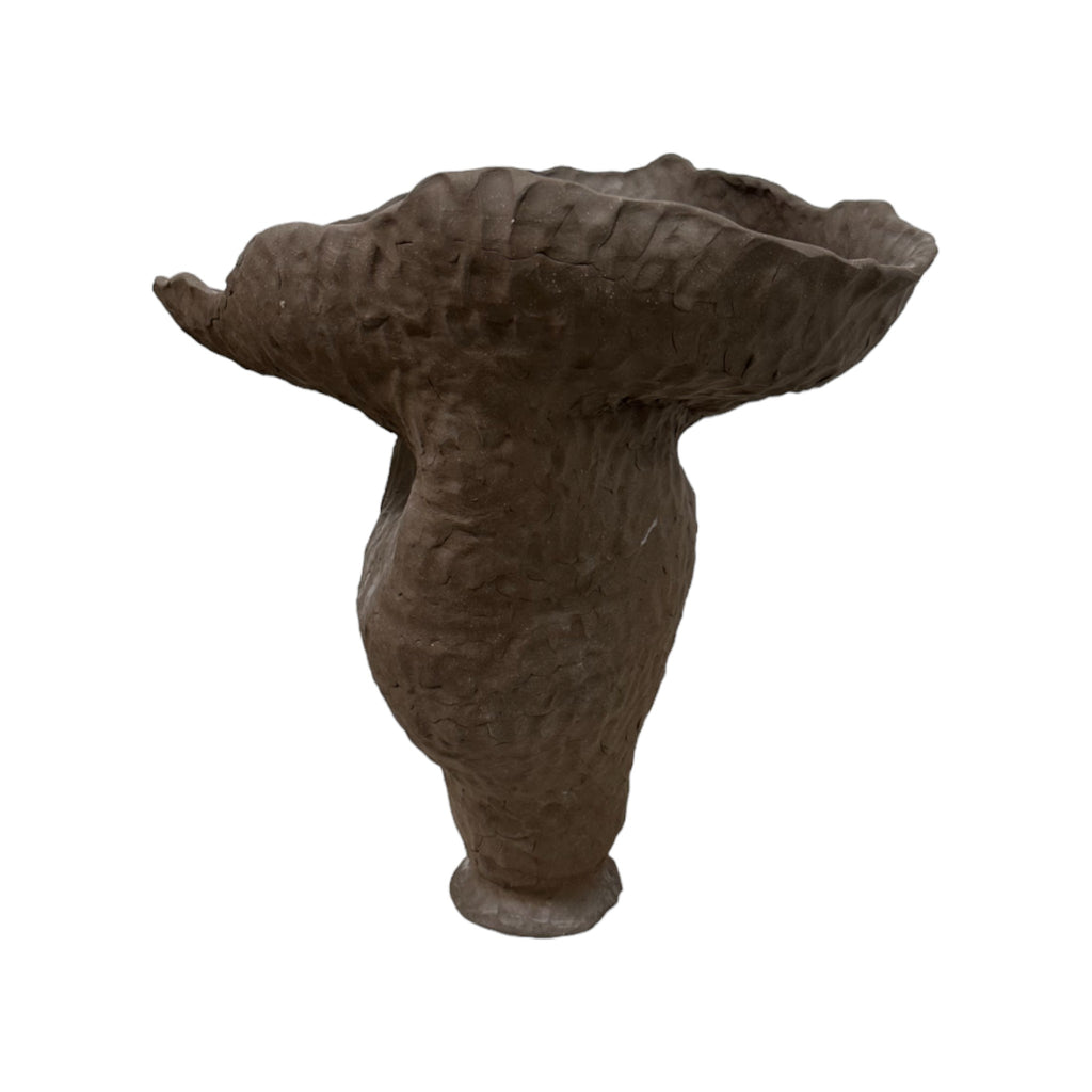 This vessel is a large, handmade ceramic piece with a rough, natural texture, like the surface of a weathered rock. It has an irregular, organic shape, flaring out widely at the top with a slightly uneven, flowing edge. The base of the vessel is narrower, giving it a sturdy yet graceful appearance. The overall texture and shape feel very earthy and tactile.