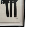 The artwork features bold, thick black brushstrokes that dominate the center of the piece. The strokes are broad, vertical, and slightly curved at the top, giving the impression of abstract columns or arches. The design is minimalist yet dynamic, typical of Pierre Soulages' style, with a stark contrast between the black shapes and the white background. The piece is framed in a sleek, black frame, enhancing its contemporary feel.