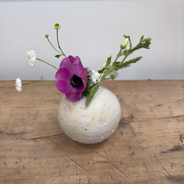 Textured cream colored ceramic bud vase shown with flowers
