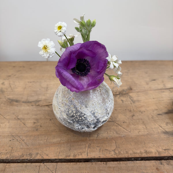 Matte glaze ceramic bud vase with crater like texture shown with flowers
