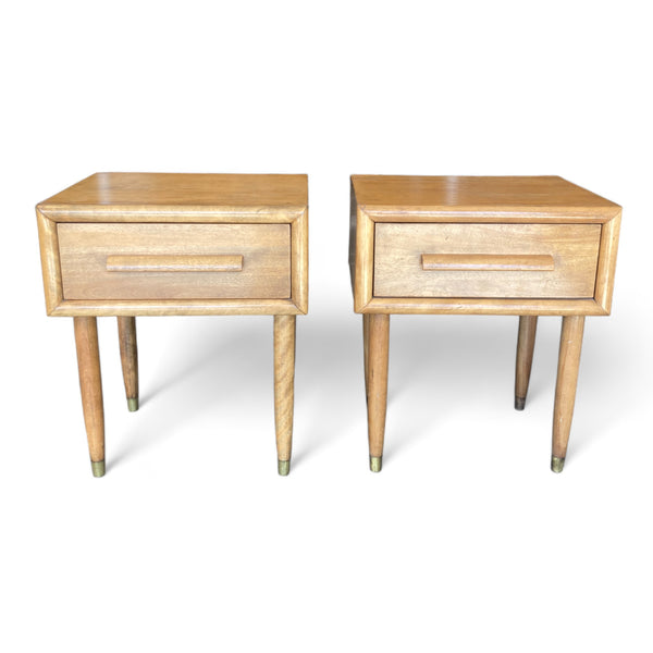A pair of midcentury modern nightstands with single drawers and tapered legs with a light oak finish. 