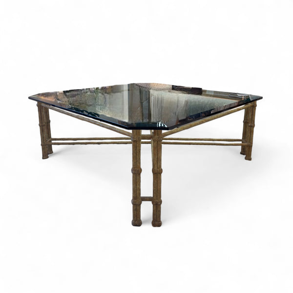 The coffee table has a painted wrought iron base with four legs and intricate scrollwork connecting them. The top is a rectangular sheet of clear glass, resting on the iron frame.