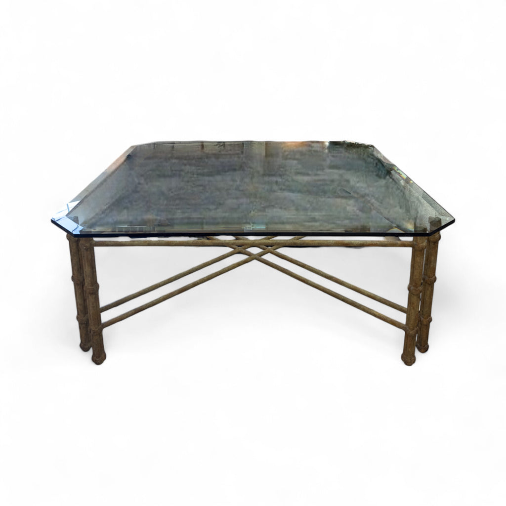 The coffee table has a painted wrought iron base with four legs and intricate scrollwork connecting them. The top is a rectangular sheet of clear glass, resting on the iron frame.