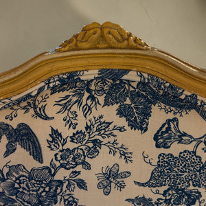 deKor vintage chair featuring a light wood frame with carved details and blue and white floral toile fabric upholstery