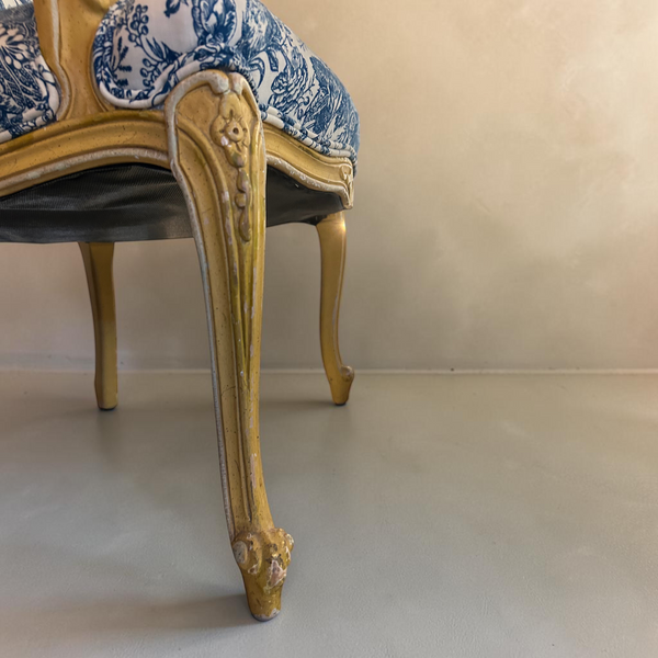 deKor vintage chair with ornate gold carved wood legs and blue and white floral upholstery on a checkered floor