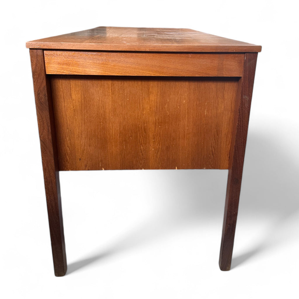 This vintage mid-century desk has a simple, rectangular design with a warm wood finish. It features two sets of drawers on each side, each with three drawers and small wooden pulls. 