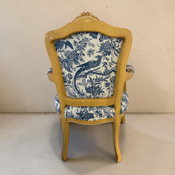Two deKor vintage chairs with distressed yellow wood frames and blue and white floral toile upholstery