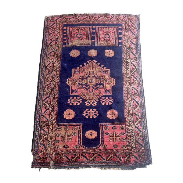 Distressed vintage Turkmen accent rug with pink border and medallion on blue background