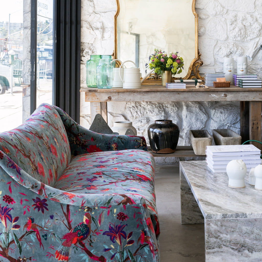 vintage blue floral velvet settee by sliding glass doors and vintage table with brass mirror