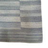 This rug has a smooth texture with horizontal stripes in different widths. The colors are soothing shades of blue, gray, and off-white, giving it a cool, relaxed feel. The stripes are evenly spaced and smooth, with no raised textures or complex designs, making the overall look simple and calming.