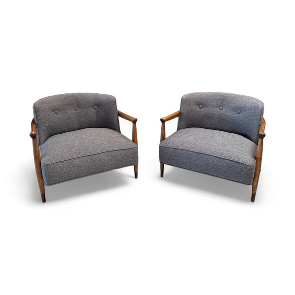 The chairs are solid and robust, with a wooden frame that elegantly curves to form the armrests and legs. The backrest and seat are generously cushioned and upholstered in a soft, textured grey fabric, providing both comfort and style. The wood has a warm, natural finish that contrasts beautifully with the grey fabric
