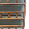 This 19th-century Provincial kitchen hutch, or "plate rack," is a tall, narrow wooden cabinet, standing freely on the floor. It has five shelves, each lined with a fabric featuring thin vertical stripes. The shelves are open at the front, with wooden slats that act like barriers to hold plates in place. The wood has a warm, aged texture, with a smooth yet slightly worn feel from years of use. The left side of the hutch has a hinge, allowing the front to swing open, secured with a simple iron latch. 