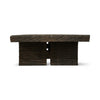 This rectangular coffee table is made of dark, textured wood. The tabletop is thick and flat, supported by two solid, block-like legs on either side. The wood appears rough and natural that add to its rustic, handcrafted appearance.