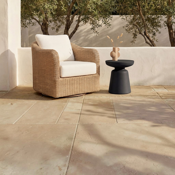 deKor compact black polypropylene outdoor side table next to a wicker patio chair on a stone terrace