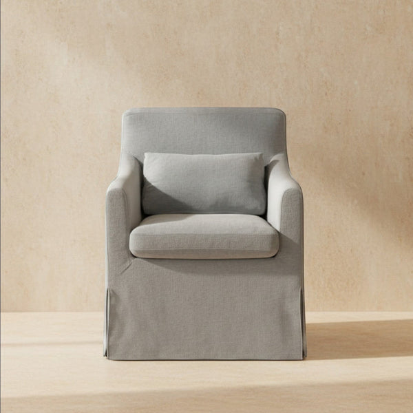 deKor blue slipcovered dining chair with curved arms, inverted pleats, and a matching lumbar pillow.