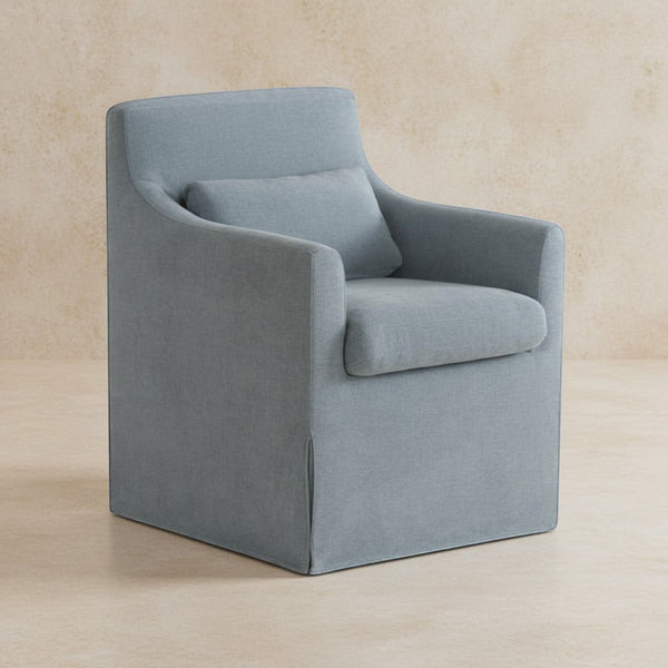 deKor blue slipcovered dining chair with curved arms, inverted pleats, and a matching lumbar pillow.