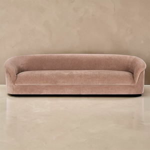 deKor blush velvet-like rolled arm sofa with a curved silhouette and four-seat capacity in a minimalist room.