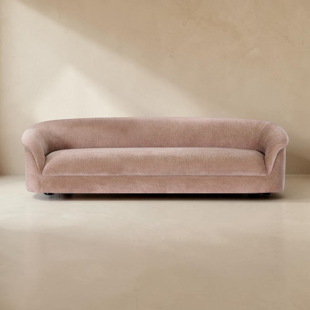 deKor blush velvet-like rolled arm sofa with a fixed back and sink-in foam cushioning in a minimalist room setting