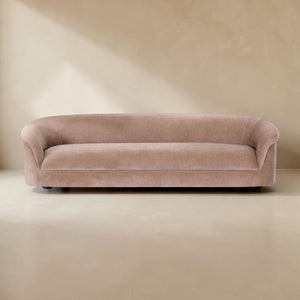 deKor blush velvet-like rolled arm sofa with a fixed back and sink-in foam cushioning in a minimalist room setting