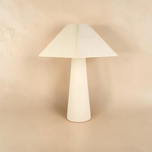 deKor cotton-wrapped table lamp with a minimalist tapered base and geometric shade in a soft cream matte finish.
