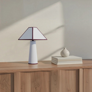 deKor cotton-wrapped table lamp with a white tapered base and geometric shade on a wooden console table.
