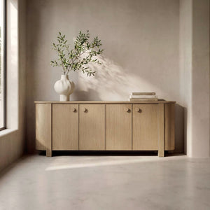 deKor natural oak sideboard with curved corners, four doors, and circular handles in a minimalist living room.