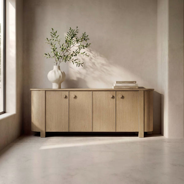 deKor natural oak sideboard with curved corners, four doors, and circular handles in a minimalist living room.