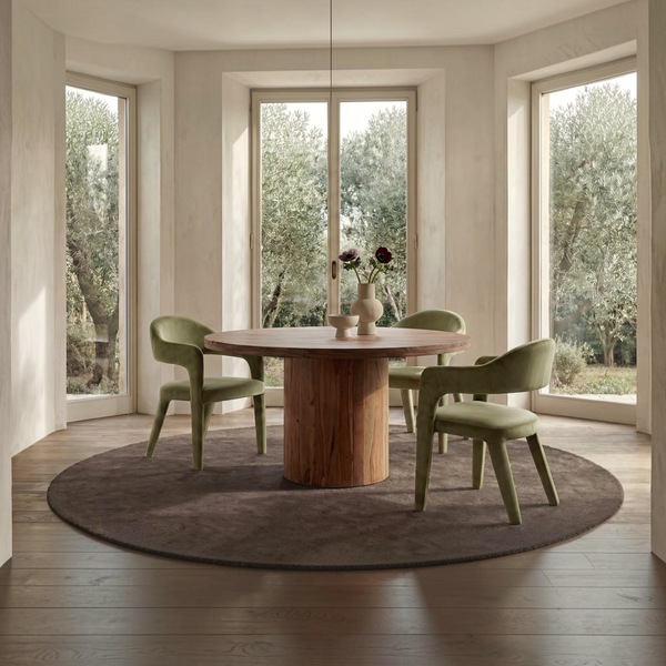 deKor green velvet barrel back dining chairs with armrests arranged around a round wooden table in a bright room