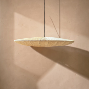 deKor large modern disk pendant light with a pleated cream fabric shade suspended against a warm beige wall