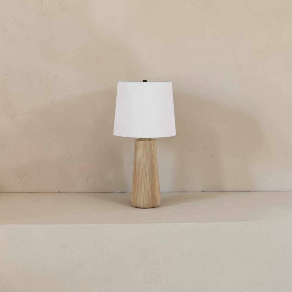 deKor table lamp with a solid natural mango wood base and a white fabric drum shade for soft ambient lighting.