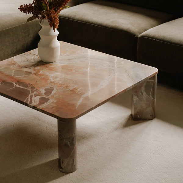 deKor Segment coffee table in orange Levante marble with a square top and rounded segmented legs in a living room.