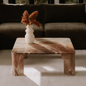 deKor orange Levante marble coffee table with a segmented base and soft rounded edges in a modern living room.