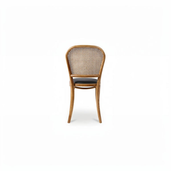 deKor rattan dining chair with a natural wood frame, woven cane backrest, and a dark polyurethane seat.