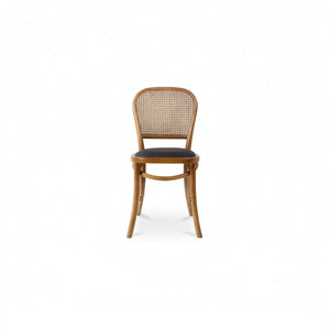 deKor rattan dining chair with a natural wood frame, woven cane backrest, and a dark black polyurethane seat.