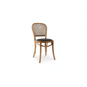 deKor rattan dining chair with a natural wood frame, woven cane backrest, and a dark polyurethane seat cushion.
