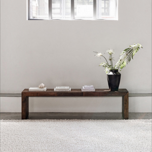 deKor salvaged large bench in light brown solid pine with rustic finish, styled with a vase and books on a rug