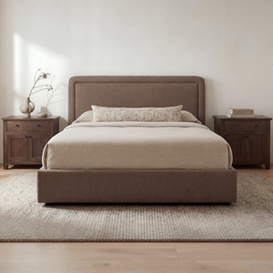 deKor Simon storage bed in brown fabric with a rounded headboard and piped detailing in a minimalist bedroom setting.
