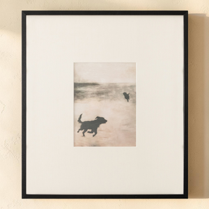 deKor Strand 2 framed print featuring silhouettes of dogs on a misty beach with earthy tones and a black wood frame